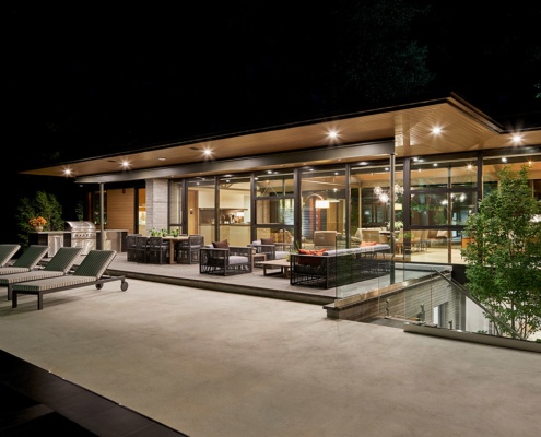 Contemporary bungalow with concrete deck, floating roof and outdoor kitchen.