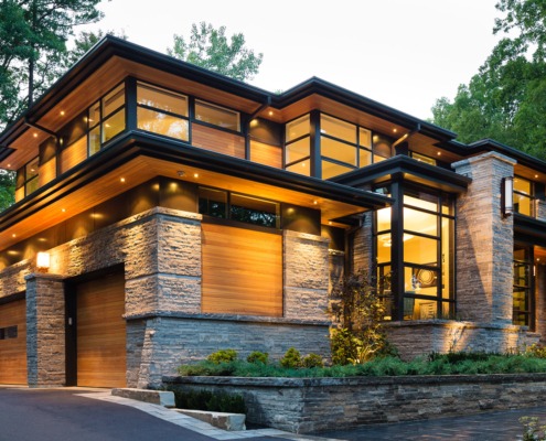 Natural modern house with wood siding, black frame windows and angled walls.