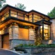 Natural modern house with wood siding, black frame windows and angled walls.