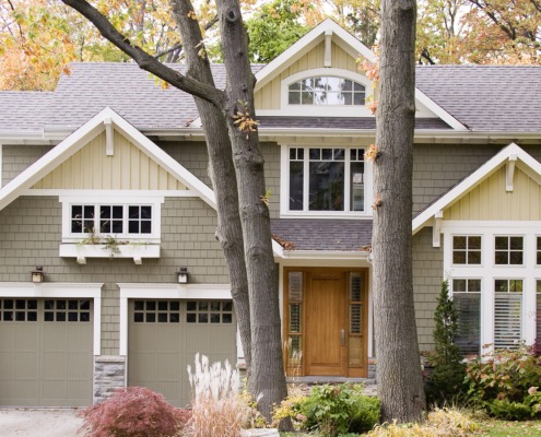 Custom home with white brackets, green garage door and grid windows.