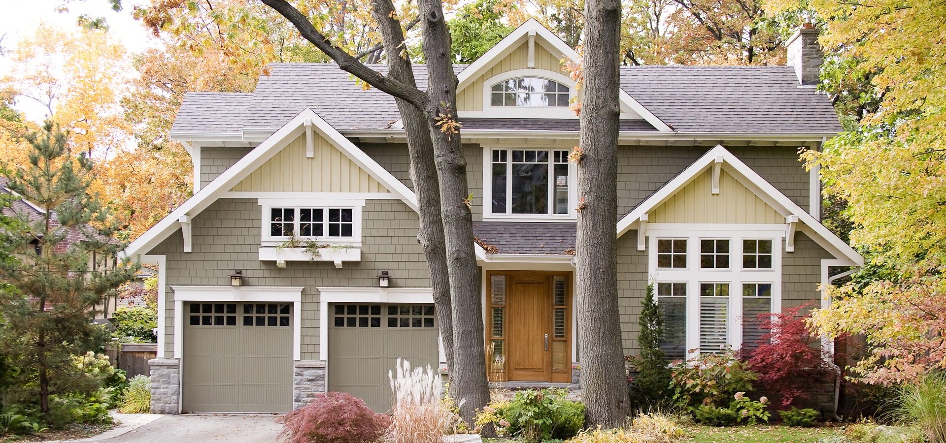 Custom home with white brackets, green garage door and grid windows.