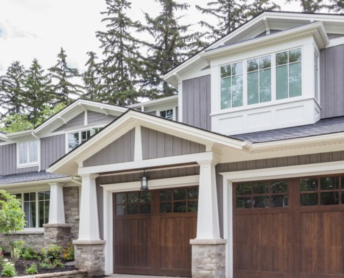 Traditional house with gray siding, white frame windows and natural stone.
