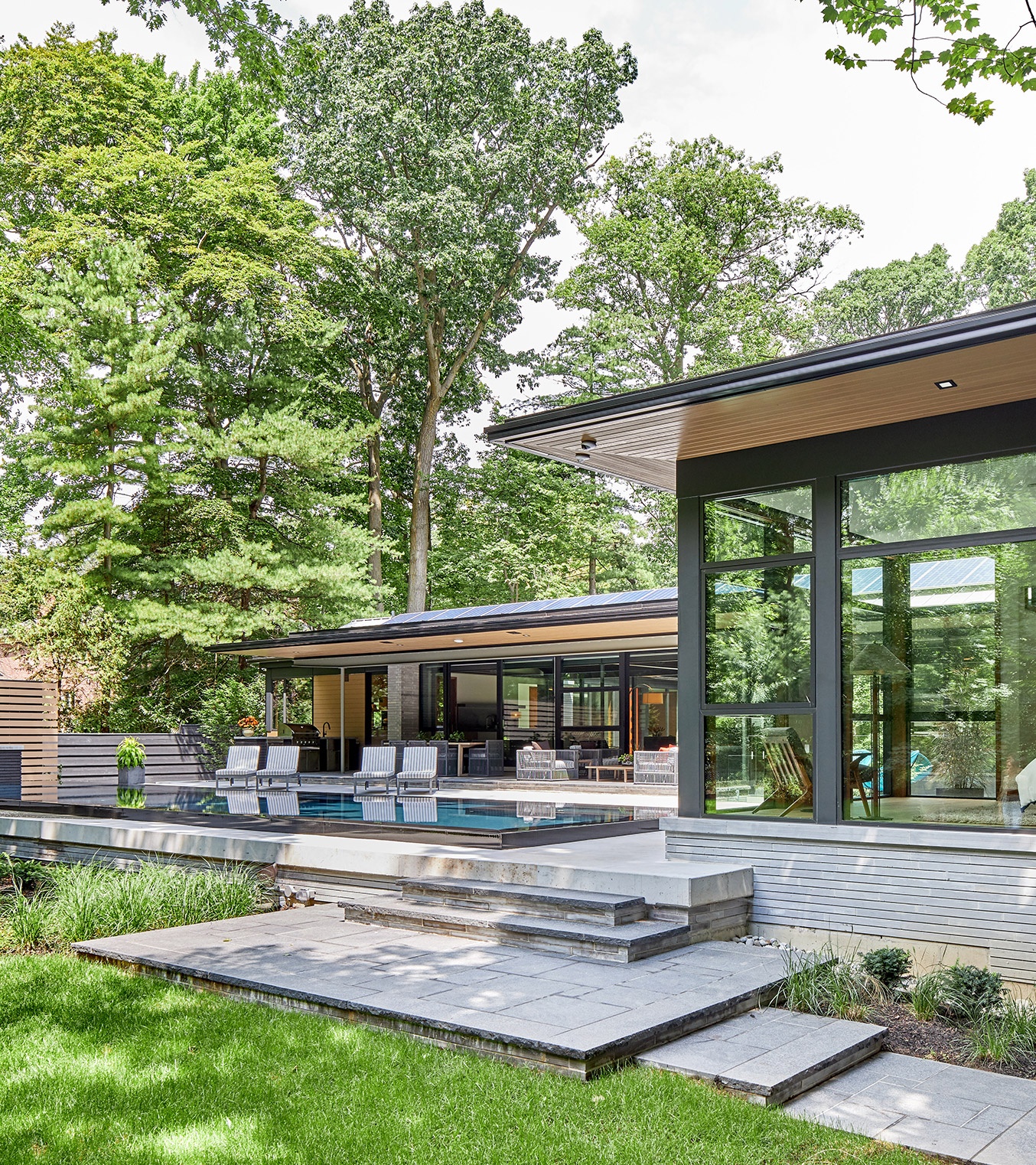 Modern bungalow with horizontal stone, corner windows and wood soffit.