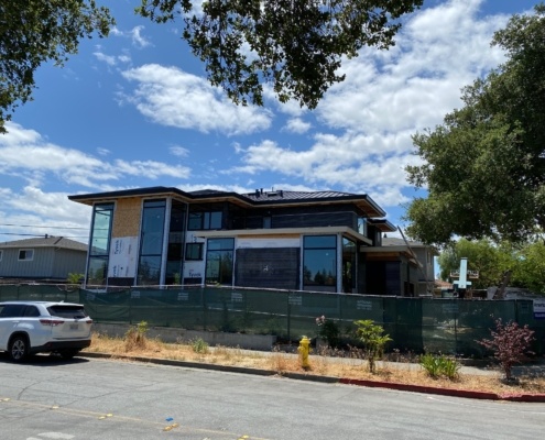 US home in construction with black frame windows, roof overhang and flat roof