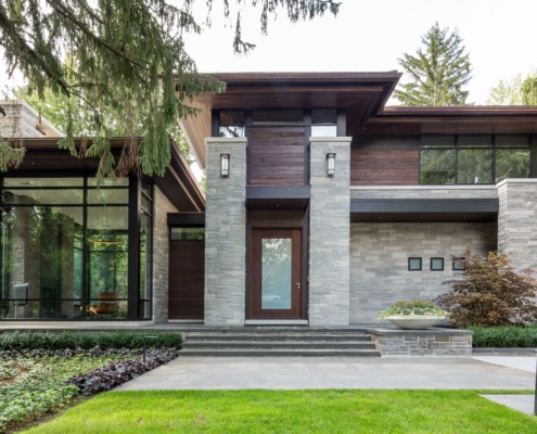 Contemporary house with wood soffit, black frame windows and wall sconce.