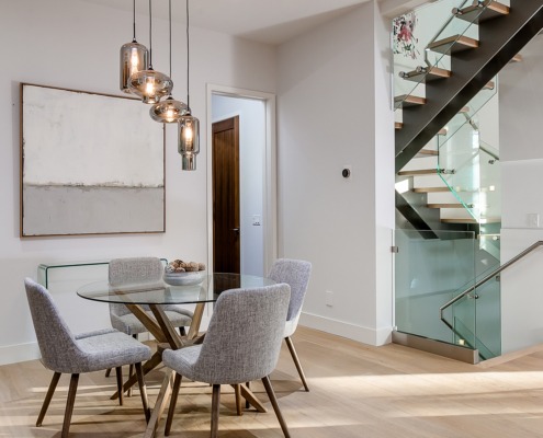 Dining room with glass dining table, hardwood floor and white baseboard.