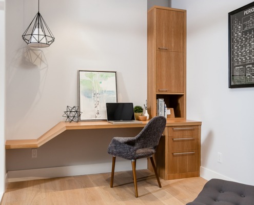 Modern office with built in desk, white frame windows and hardwood floors.