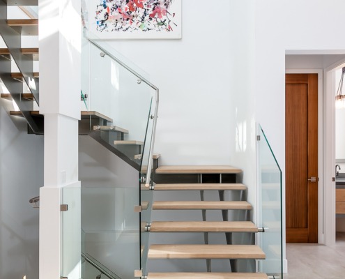 Modern stair with metal railing, white baseboard and white walls.