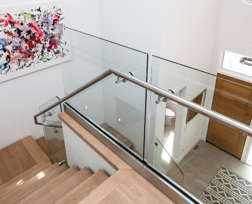 Floating stair with wood treads, glass railing and modern chandelier.