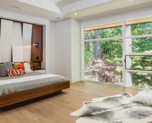 Master bedroom with wood shelves, white frame window and wood floor.