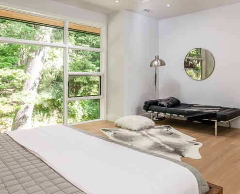 Master bedroom with white frame window, hardwood floor and white baseboard.