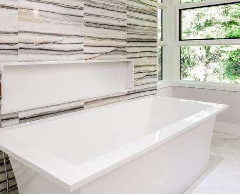 Modern bathroom with tile floor, freestanding tub and corner window.