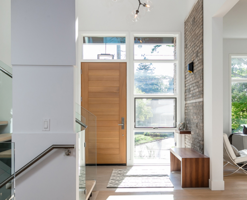 Home front entry with wood front door, exposed stone wall and modern stair.