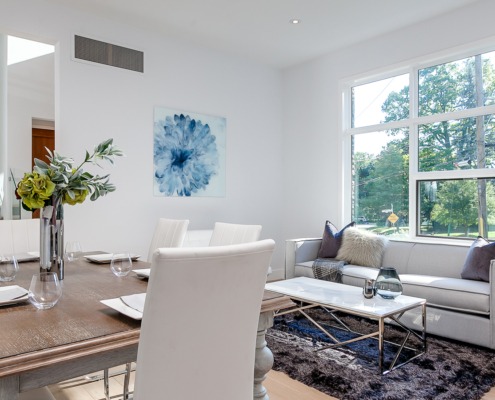 Dining room with wood table, white frame window and white chairs.