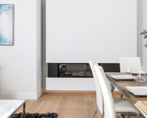 Dining room with floating fireplace, wood dining table and wood floor.