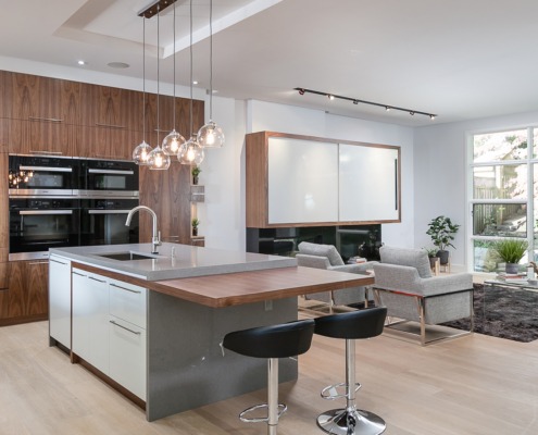 Open concept house with gray island, hardwood floor and white frame window.