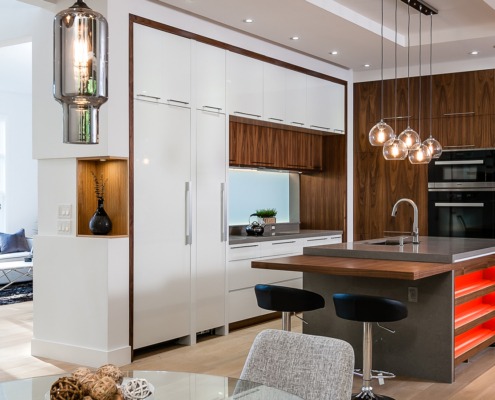 Contemporary kitchen with hardwood floor, white cabinets and black barstools.