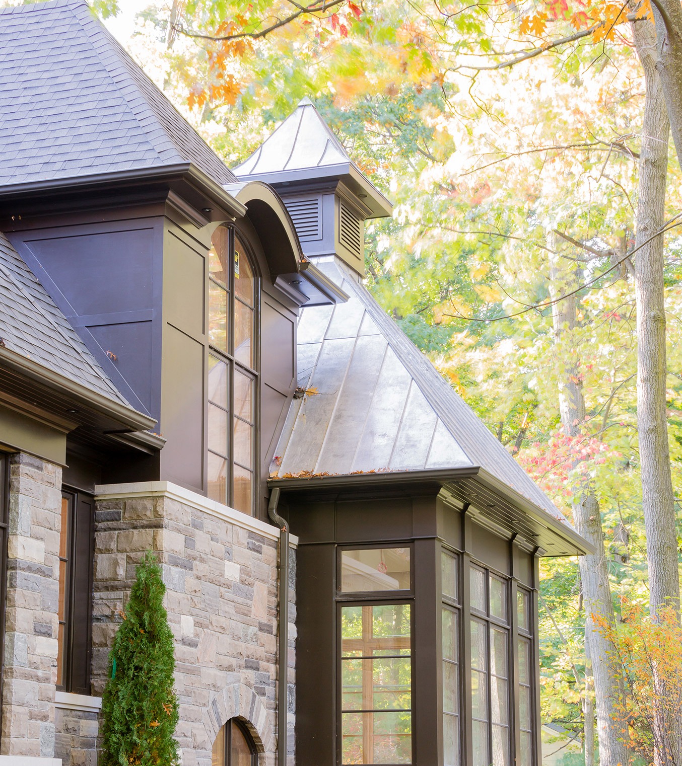 Traditional home with metal roof, natural stone and dark frame windows.