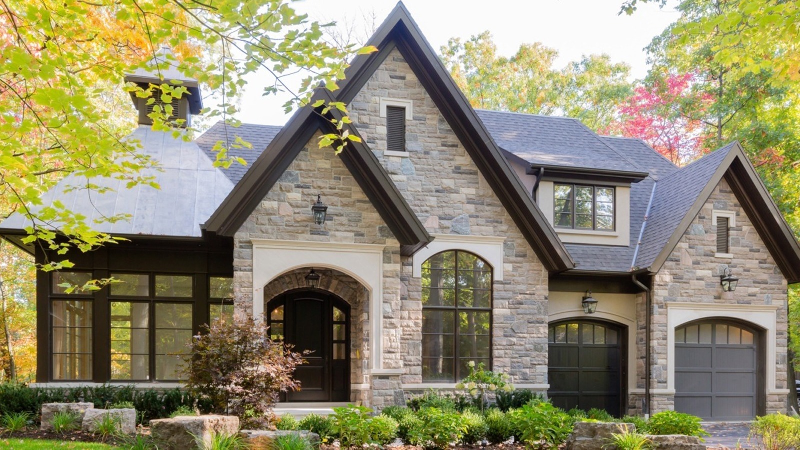 Custom home with arched window, natural stone and metal roof.