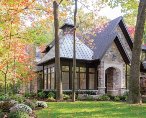 Stone house with black frame window, cupola and shingled roof.