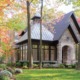 Stone house with black frame window, cupola and shingled roof.