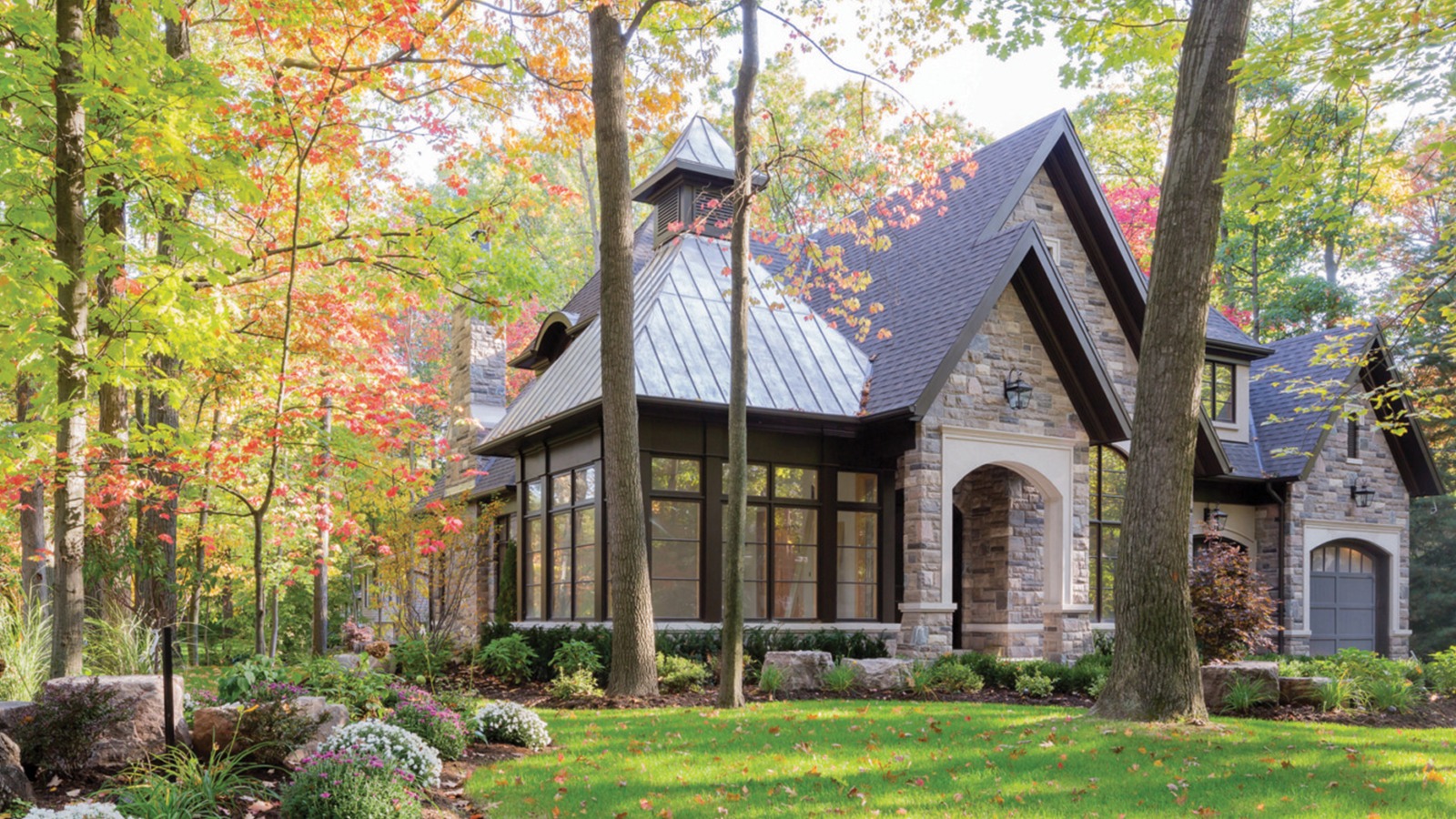 Stone house with black frame window, cupola and shingled roof.