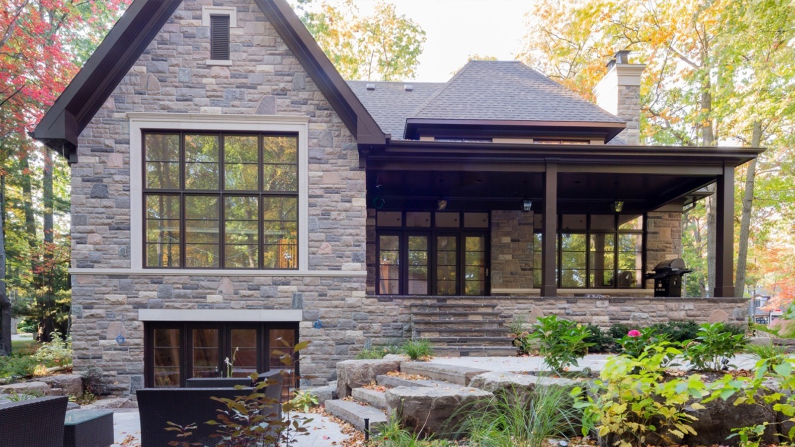 Stone house with black frame windows, covered porch and stone steps.