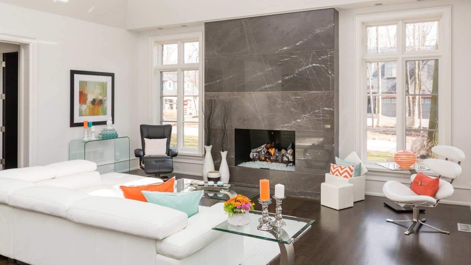 Family room with stone fireplace, white frame window and wood floor.