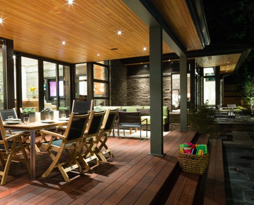 Outdoor deck with wood floor, steel columns and wood dining table.