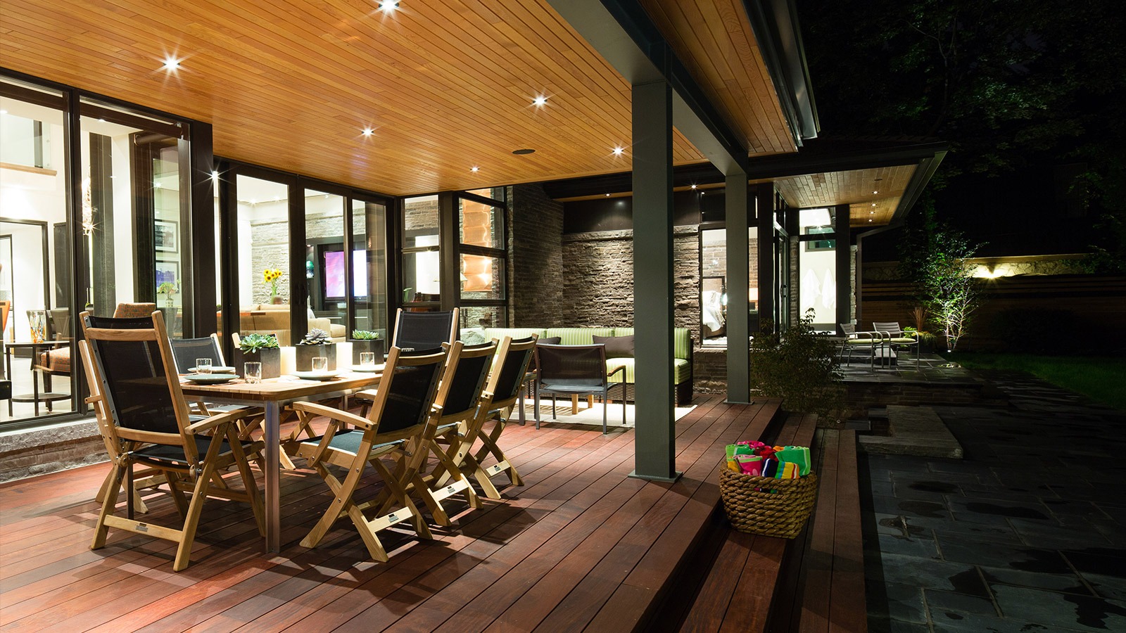 Outdoor deck with wood floor, steel columns and wood dining table.