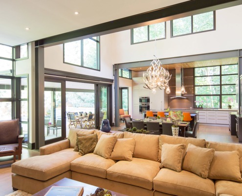 Living room with steel beam, black frame windows and white walls.