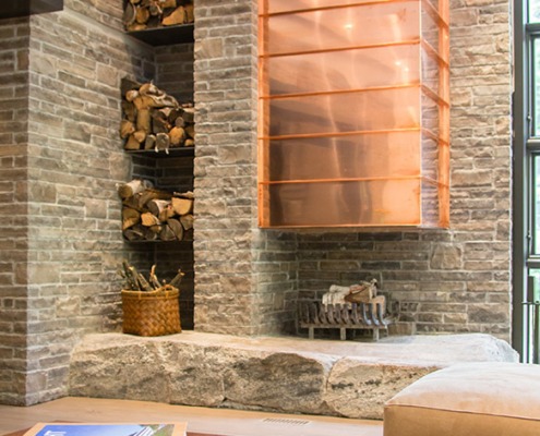 Modern family room with exposed stone, built in cabinets and beige couch.