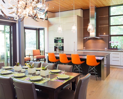 Contemporary kitchen and dining room with metal chandelier, wood dining table and hardwood floor.