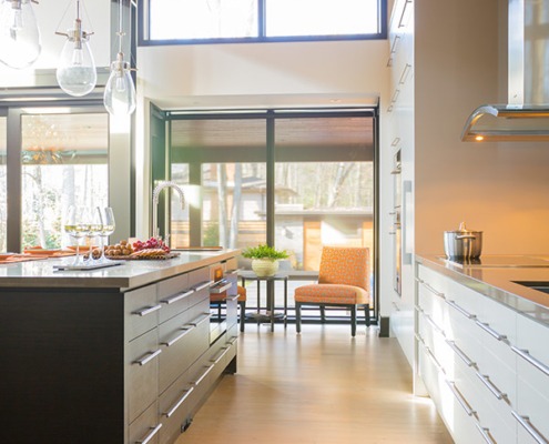 Home kitchen with white drawers, hardwood floor and range hood.