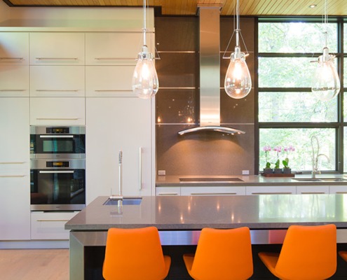 Modern kitchen island with gray island, pendant lights and wood ceiling.