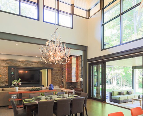 Open concept living area with large windows, vaulted ceilings and modern chandelier.