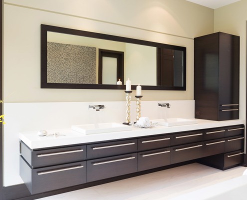 Modern bathroom with wood drawers, tile floor and black frame windows.