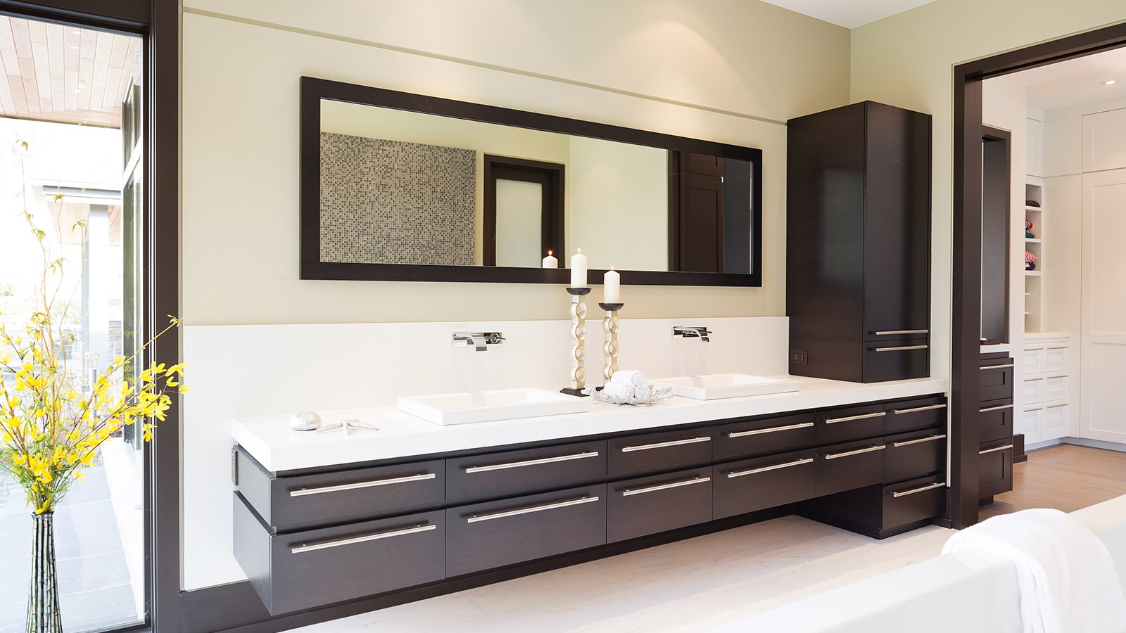 Modern bathroom with wood drawers, tile floor and black frame windows.