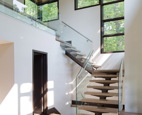 Home front entry with floating staircase, vaulted ceilings and dark trim.