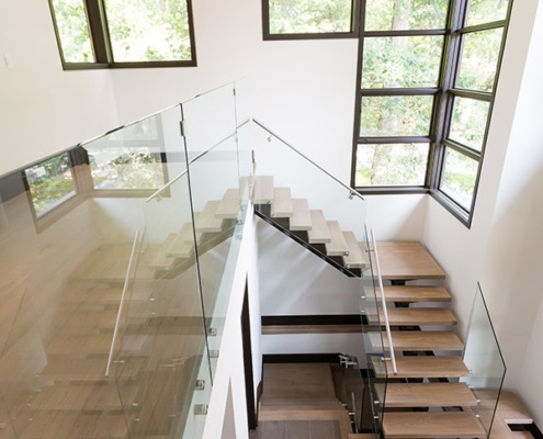 Floating staircase with corner windows, wood treads and tile floor.