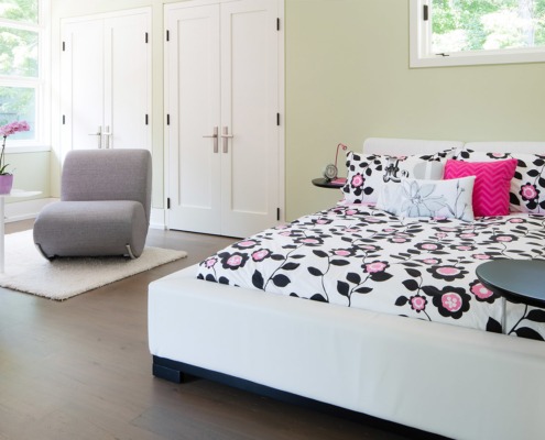 Childrens bedroom with hardwood floor, white furniture and white frame window.