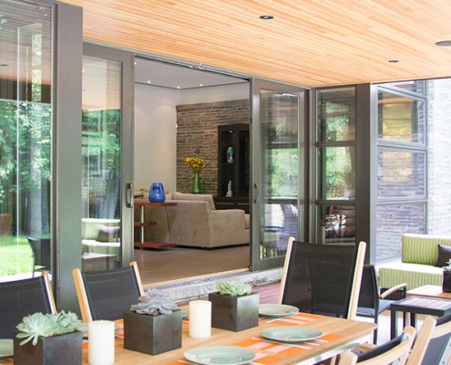 Outdoor home dining with wood floor, black chairs and corner window.
