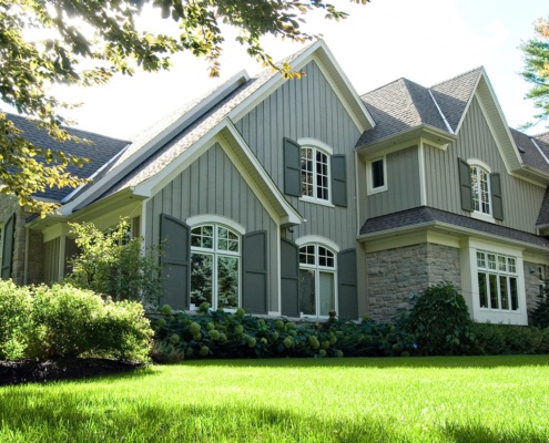 Traditional house with gables, white windows and stone siding.