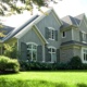 Traditional house with gables, white windows and stone siding.