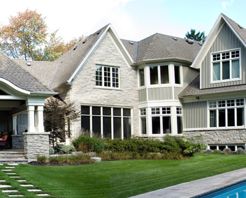Traditional architectural design with green siding, stone siding and white trim.