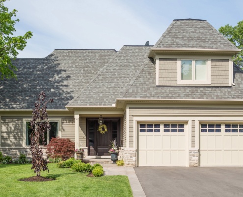 Oakville home with natural stone siding, wood front door and light trim.