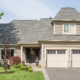 Oakville home with natural stone siding, wood front door and light trim.