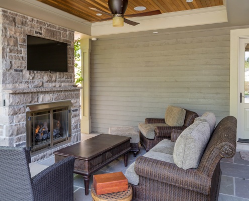 Backyard patio with fireplace, wood siding and wood ceiling.