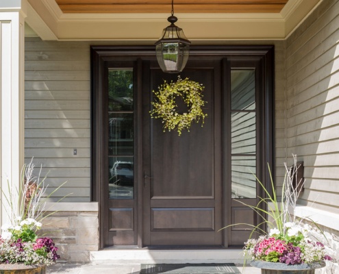 Front entry of traditional home with wood siding, natural stone and wood door.