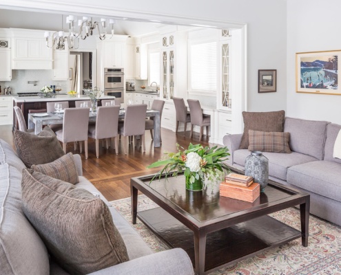 Family room with hardwood floor, white trim and gray couches.